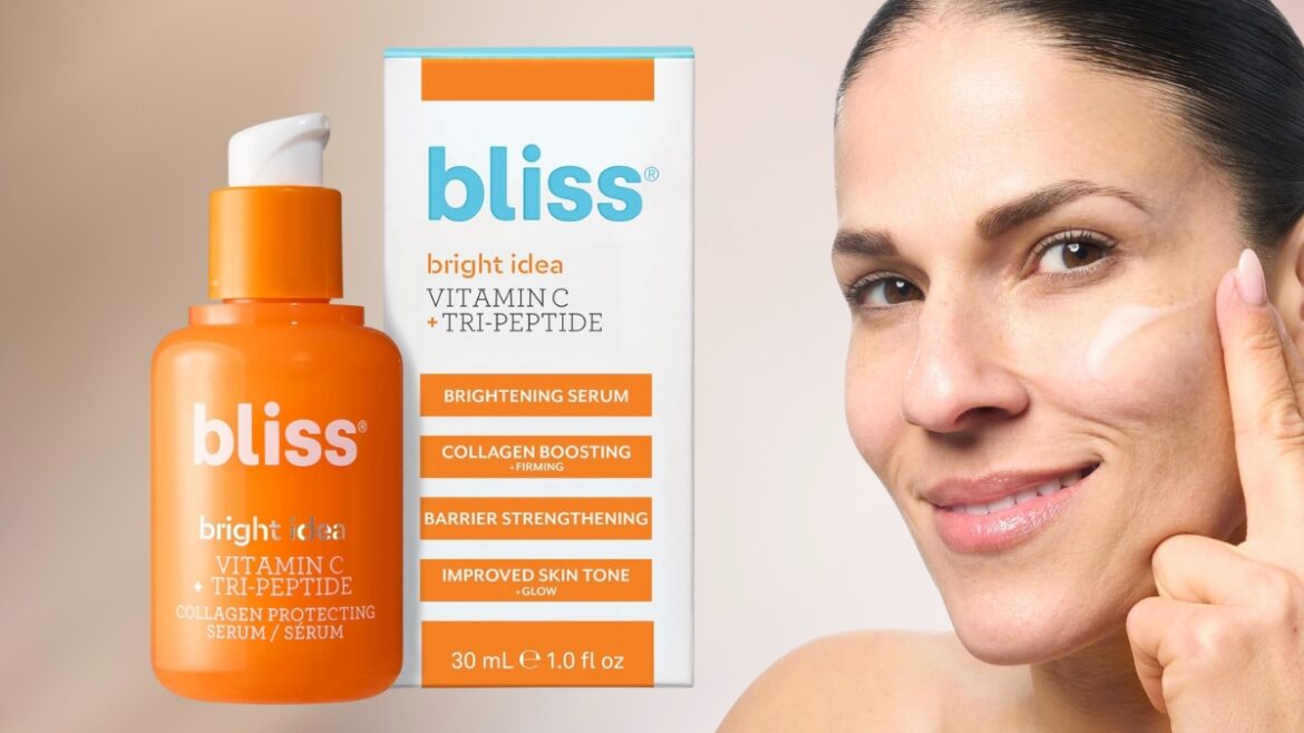Woman applying Bliss Vitamin C Serum with the product bottle and packaging shown beside her face.