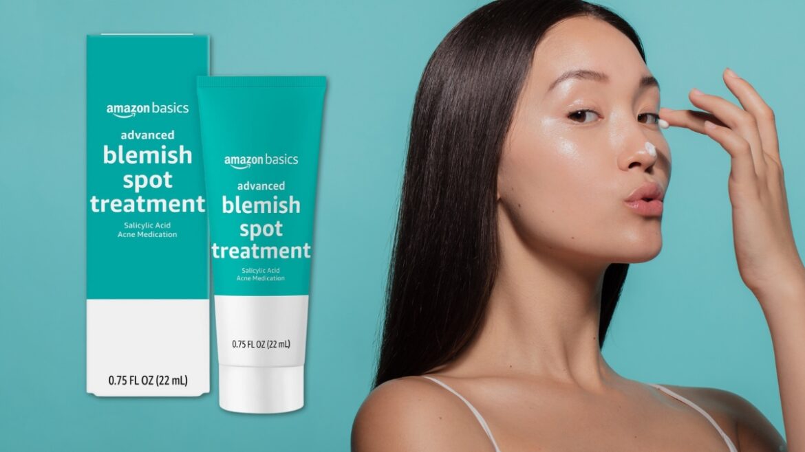 A woman applies Amazon Basics Salicylic Acid Spot Treatment to her nose with the product box shown beside her.