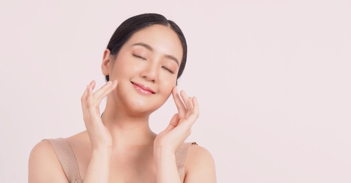 Woman with clear glowing skin gently touching face during skincare routine