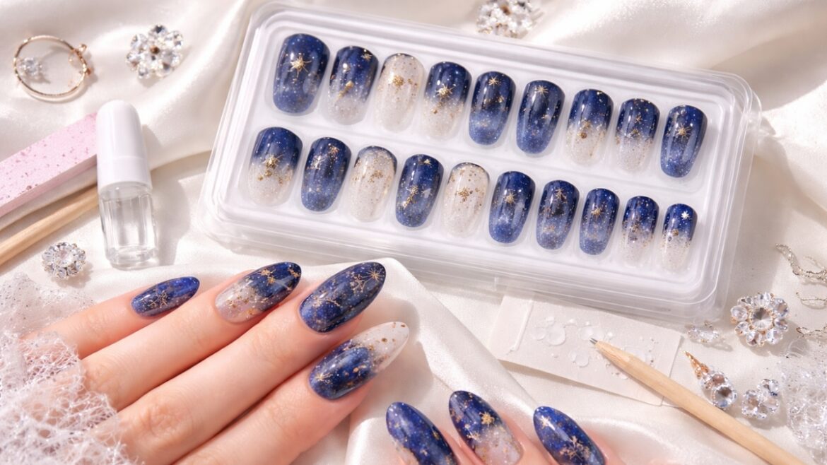24-piece blue galaxy press-on nails with gold star accents in almond shape displayed in a clear storage case with nail glue and manicure tools on satin fabric background